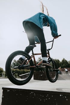 A BMX rider executes an impressive trick on a ramp in an outdoor skatepark during the day.