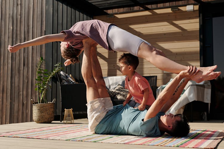 A Man Lying Down While Lifting A Woman