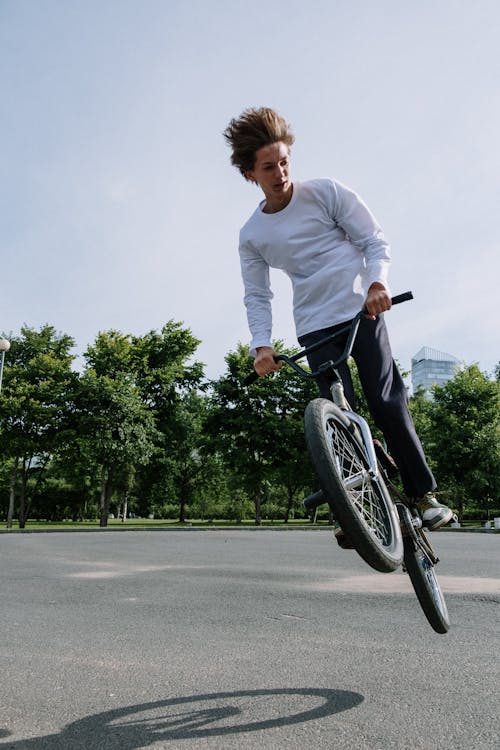 A Man Wearing White Sweater while Riding a Bike · Free Stock Photo