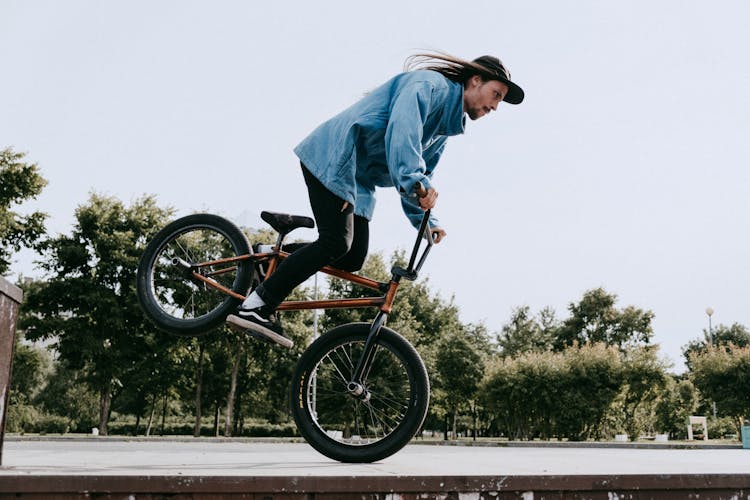 A Side View Of A Man Wearing Denim Jacket While Riding A Bike