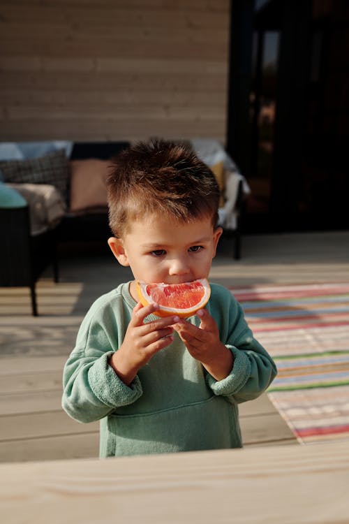 A Young Boy Eating Grapefruit