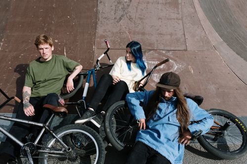 Free Three friends resting at a skatepark with BMX bikes, enjoying leisure time outdoors. Stock Photo