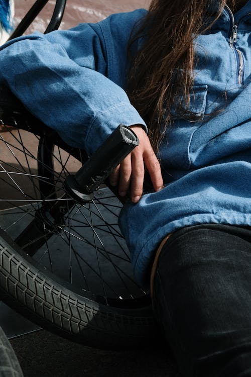 Free Person in Blue Long Sleeves Sitting on a Bicycle Wheel Stock Photo