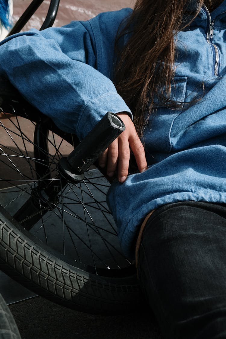 Person In Blue Long Sleeves Sitting On A Bicycle Wheel