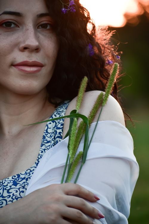 Free Young smiling female looking at camera in meadow with green grass in bright sunlight in summer in back lit Stock Photo