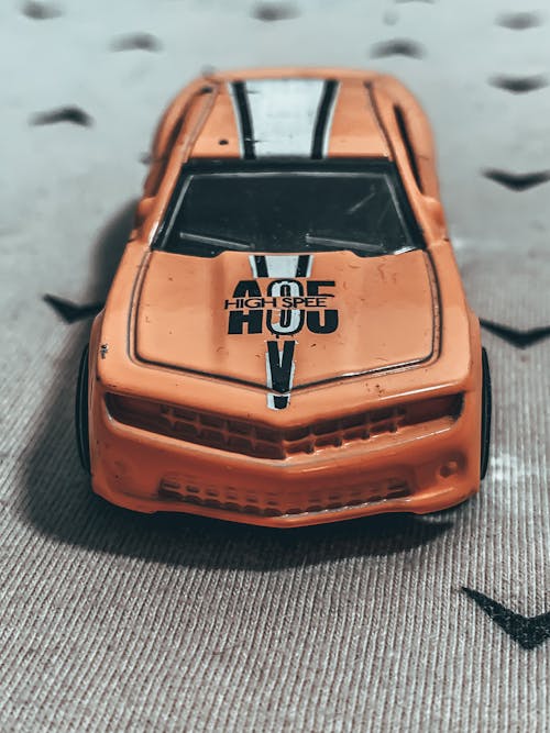 Free From above of small miniature of weathered orange toy car placed on rough carpet Stock Photo