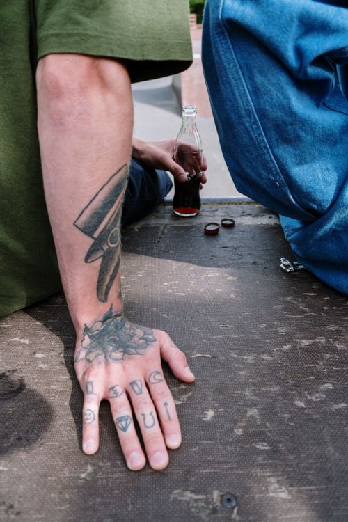 Free A tattooed hand rests on a surface with a bottle in the background, offering a gritty urban vibe. Stock Photo