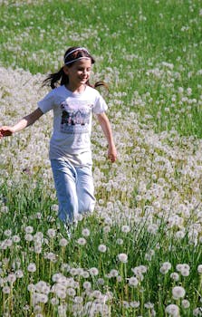 阳光明媚的日子里，一个年轻女孩快乐地跑过开满鲜花的郁郁葱葱的田野