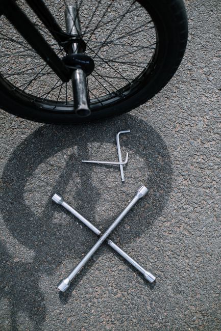 Bicycle wheel with tools on pavement, ideal for cycling maintenance themes.