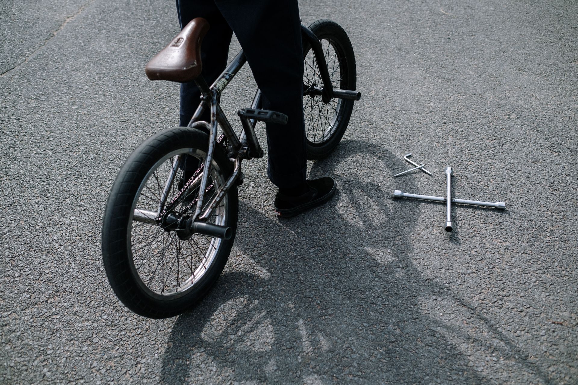 BMX bike parked on pavement with tools nearby, hinting at maintenance or repair work.