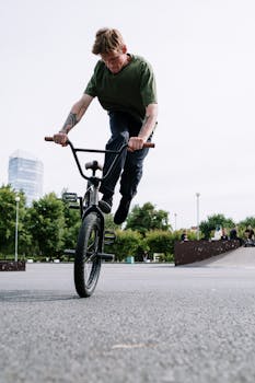 Man in green shirt executing BMX trick in an outdoor skate park.