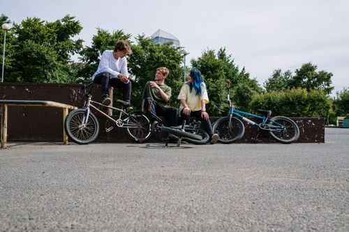 Free Group of teenagers conversing at skatepark with BMX bikes on a sunny day. Stock Photo