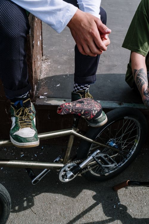Free BMX rider sitting on bike at a skate park, showcasing casual style and tattoos. Stock Photo