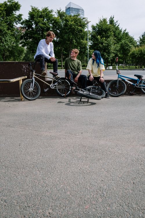 Free Three friends with BMX bikes having a conversation at an outdoor skatepark. Stock Photo