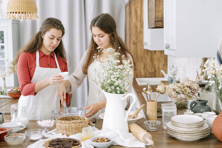 Two Women Mixing Ingredients In A Glass Bowl