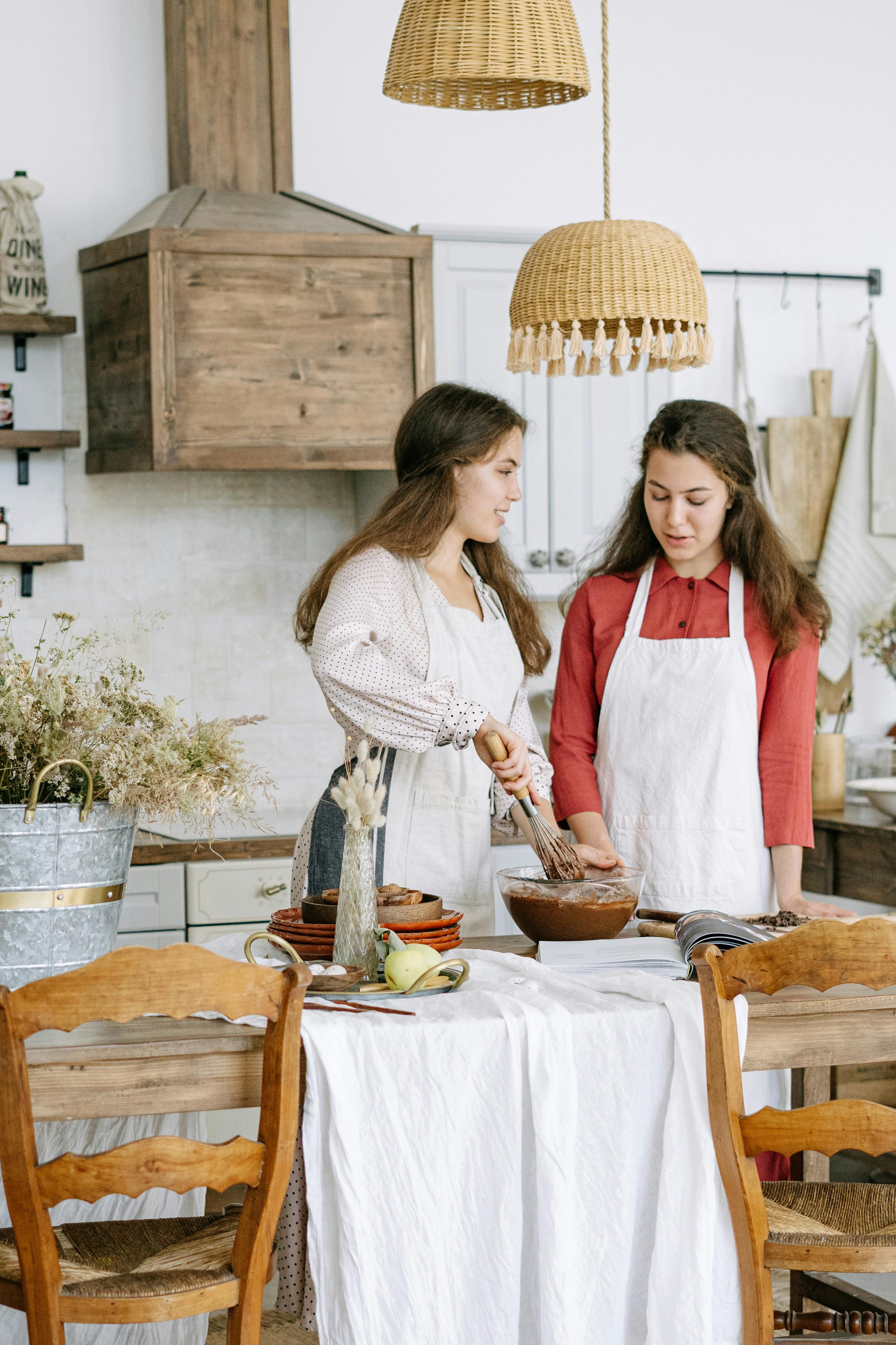 在舒适的乡村厨房里，两名年轻女子穿着围裙一起烘焙