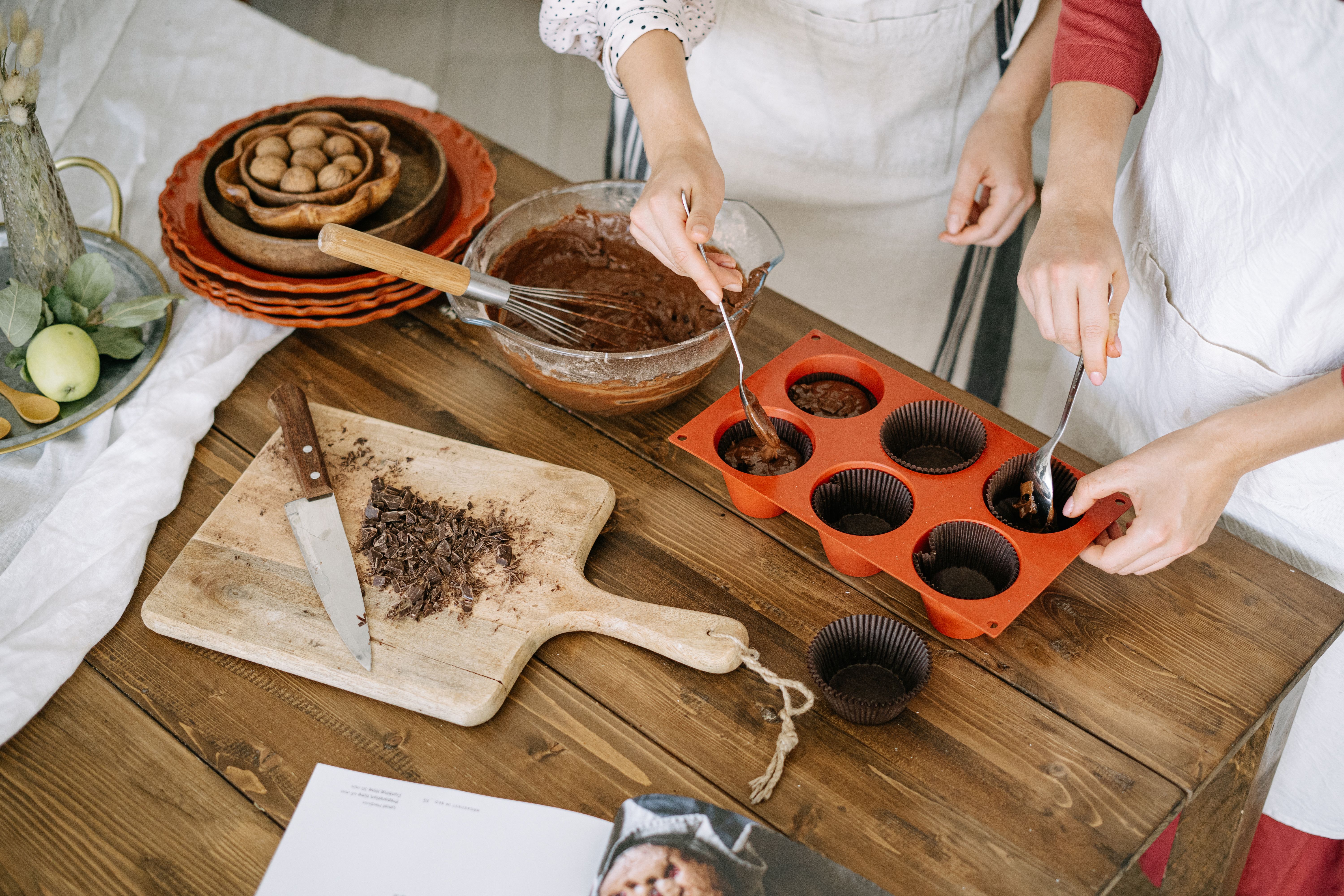 Close-up of hands making homemade chocolate cupcakes with ingredients and utensils.