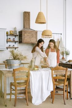 Two women enjoy baking together in a cozy rustic kitchen setting, capturing warmth and togetherness.