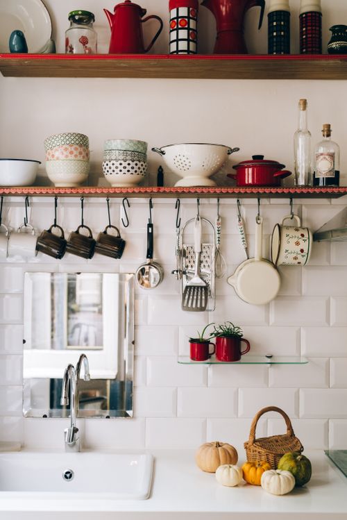 Free Cozy kitchen shelf with hanging utensils, colorful bowls, and rustic decor creating a warm atmosphere. Stock Photo