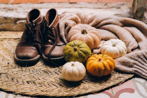 Free Cozy fall scene features pumpkins on woven mat with brown leather shoes indoors. Stock Photo