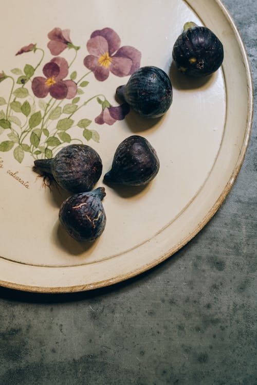 Free From above of tasty ripe figs on round plate with floral ornament on marble table Stock Photo