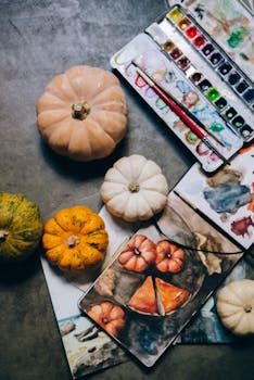 灰色背景上，南瓜和水彩艺术用品的顶视图