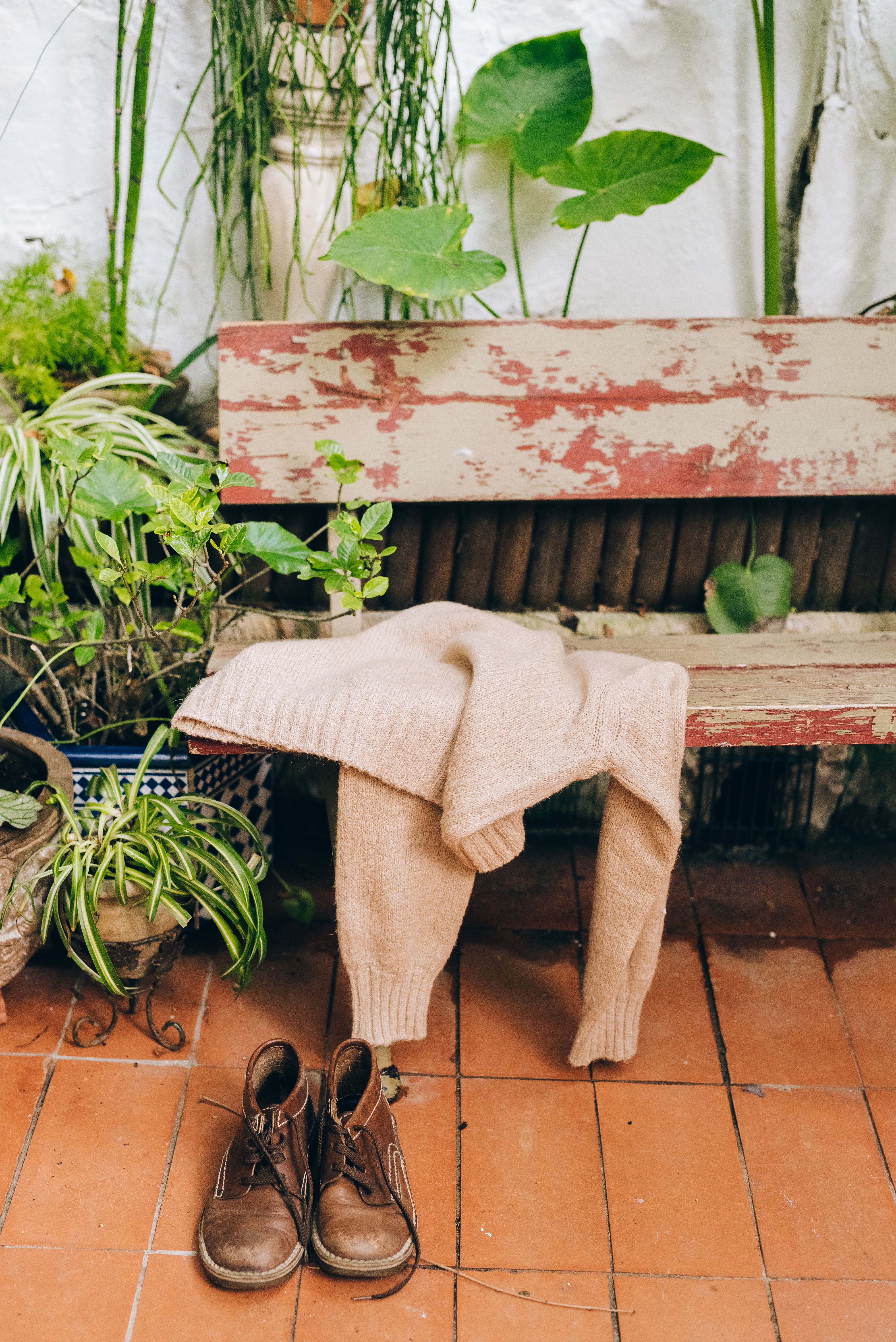 在乡村庭院里，舒适的毛衣、靴子和郁郁葱葱的绿色植物点缀着饱经风霜的长凳