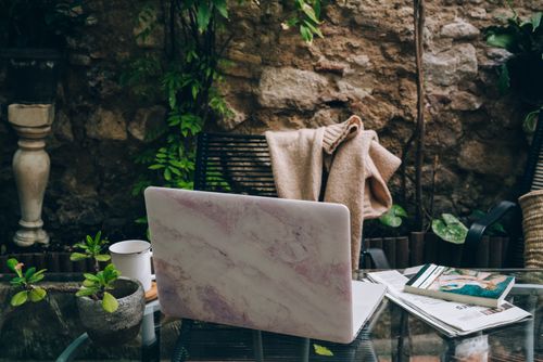 Free A serene outdoor workspace setup with a marble laptop, coffee cup, and plants for a productive environment. Stock Photo