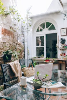 A bright indoor garden workspace with a laptop on a glass table, perfect for remote work.