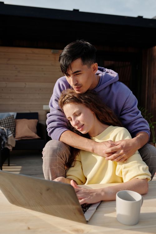 Free A loving couple enjoying quality time outdoors with a laptop, embracing each other. Stock Photo
