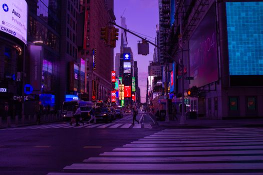 Illuminated Times Square with busy pedestrian crossing at night, showcasing vibrant city life in New York.