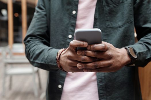 Close-up of person using smartphone indoors, showcasing casual fashion accessories.
