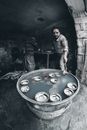 From above of ethnic male worker cooling metal bowls in container with water using tongs near unrecognizable partner