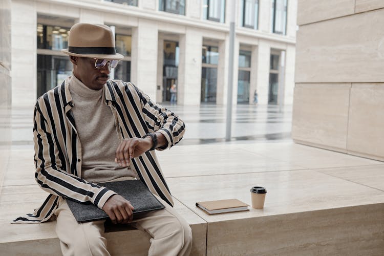 Fashionable Man Wearing A Hat Looking At The Time