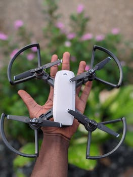 Close-up of a drone held in hand against a blurred garden backdrop, showcasing technology and nature.