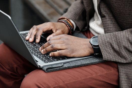 A professional typing on a laptop keyboard with a focus on hands, style, and attire.