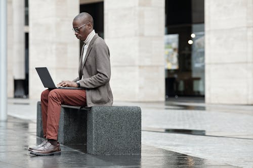 Man Sitting on Bench While Using a Laptop
