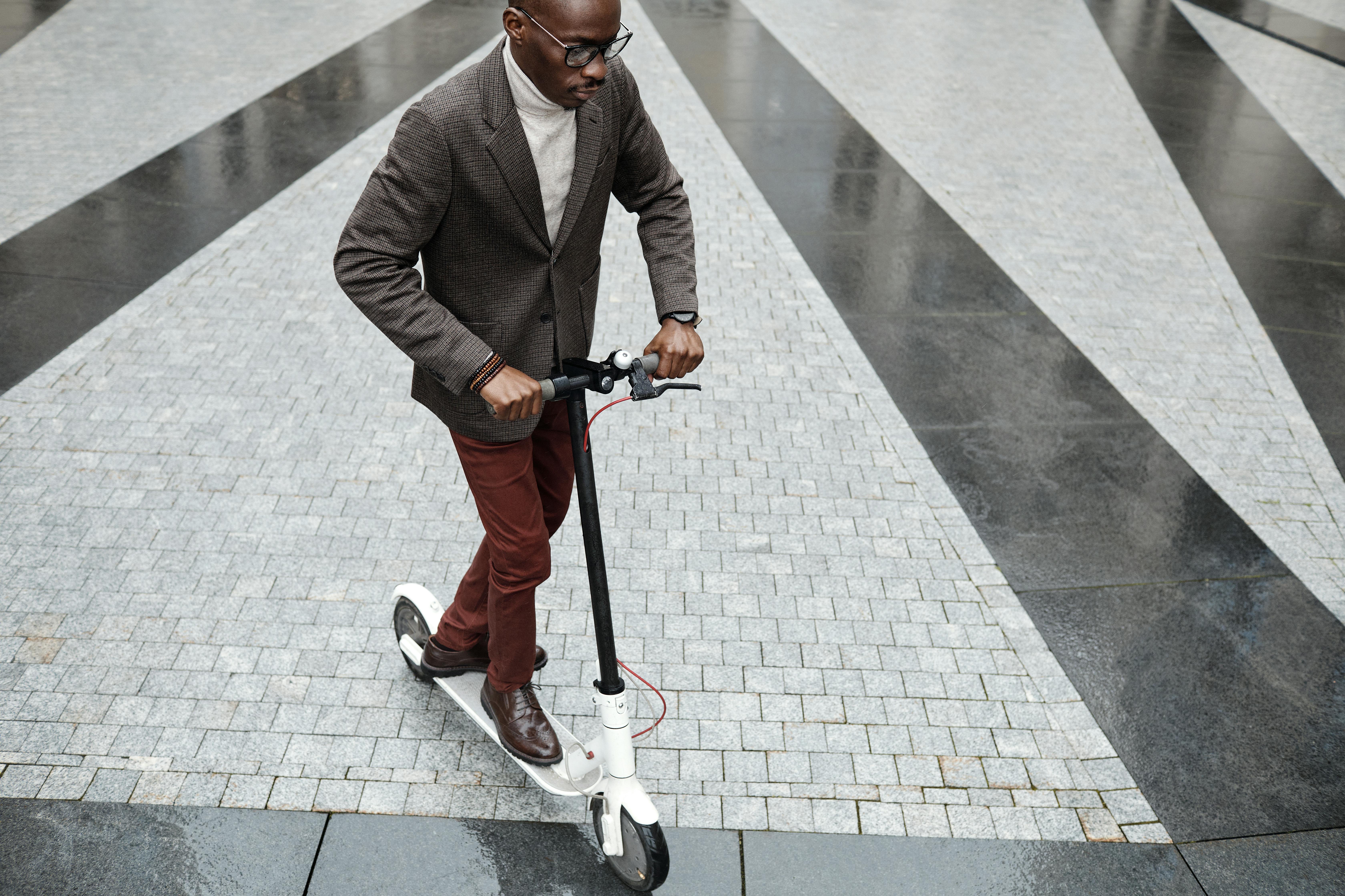 Free A fashionable adult male rides an electric scooter on modern city pavement. Stock Photo