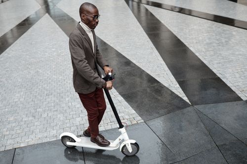 Free A fashionable adult man riding an electric scooter on a modern city pavement. Stock Photo