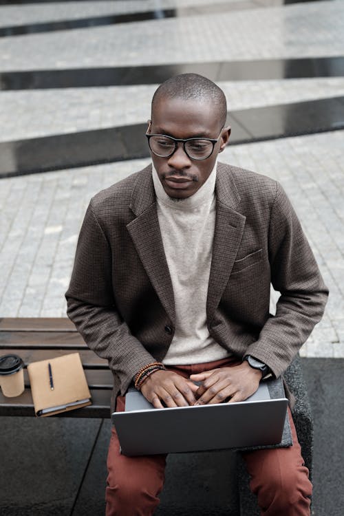 Elegant Man Sitting on Bench with Laptop