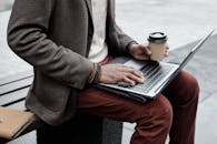 A Stylish Person Using a Laptop while Holding a Cup of Coffee
