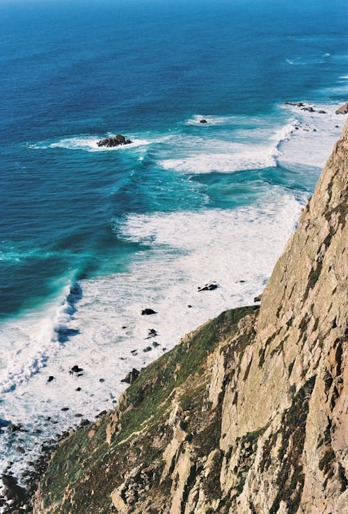 A Blue Sea with Seafoam Beside a Cliff