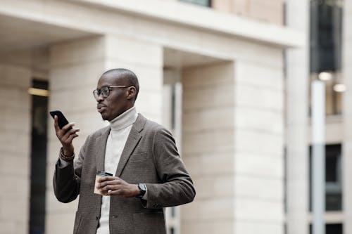 Free Man in Gray Suit Jacket Holding Smartphone Stock Photo