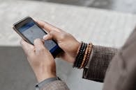 Person Wearing Bracelets Holding Black Phone