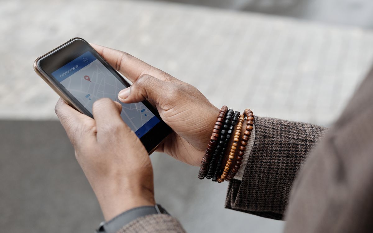 Close-up of hands with bracelets navigating on smartphone using GPS app outdoors.