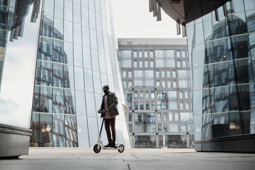 Man riding a scooter through an urban cityscape with reflective buildings highlighting modern commuting.