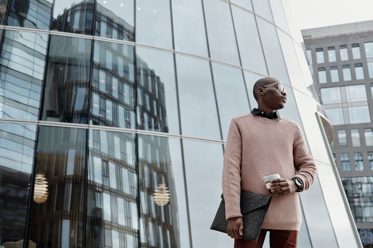 Man Standing Outside A Building Carrying An Envelope