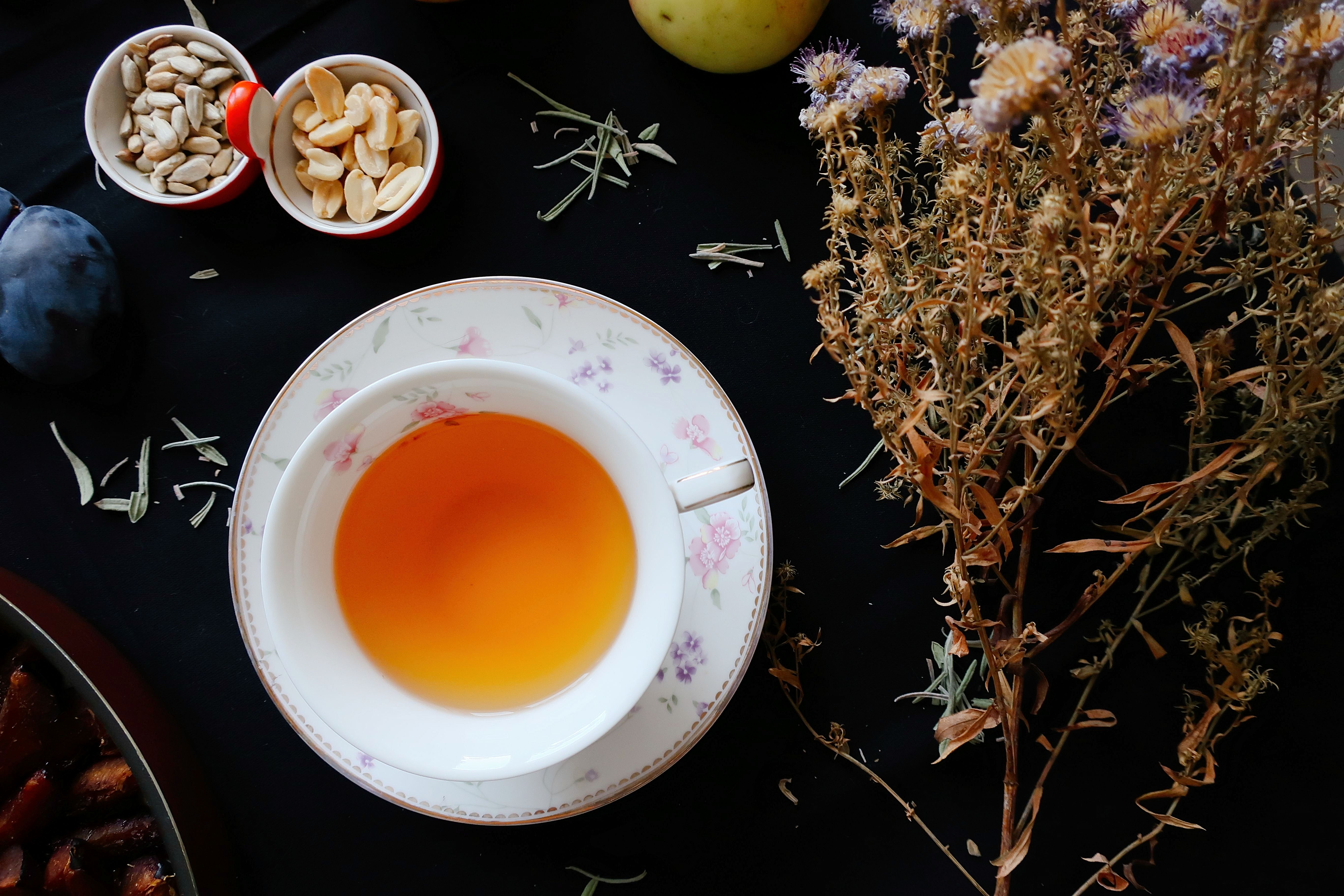 A warm cup of tea with dried flowers and nuts, creating a cozy and inviting ambiance.