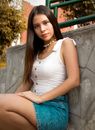 Woman in White Tank Top and Blue Denim Shorts Sitting on Concrete Bench