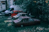 From above of retro automobiles and multi seat passenger car parked in green yard in suburb